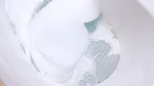 Photo une baignoire blanche moderne remplie d'eau courante d'un robinet en nickel brossé