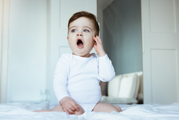 Le bâillement bébé garçon enfant sur le lit. Portrait d'enfant, prêt à dormir vue latérale