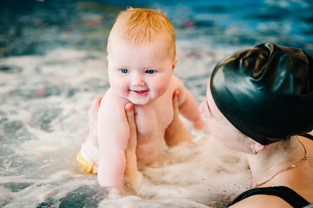 Bain à remous, jacuzzi. Plongée bébé dans la pataugeoire. Jeune maman, instructeur de natation et heureuse petite fille dans la piscine. Apprenez à nager. Profitez de la première journée de baignade dans l'eau.