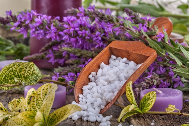 Bain de sel dans une cuillère en bois avec des fleurs et des feuilles en arrière-plan