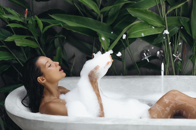 Photo bain et soin du corps jour de spa femme dans la baignoire intérieur de la salle de bain tropicale