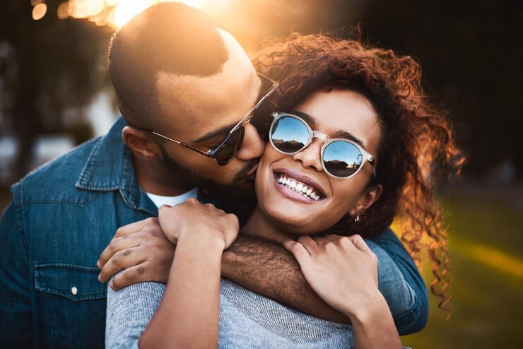 Photo baiser et couple dans le parc lunettes de soleil et la romance avec la relation aventure et se lier ensemble outdoor embrasser ou heureux homme avec femme paisible et vacances avec confiance excité ou gentillesse