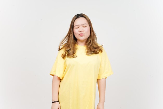 Baiser soufflant de belle femme asiatique portant un T-shirt jaune isolé sur fond blanc