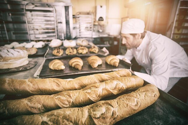 Baker contrôle du pain fraîchement cuit dans la cuisine de la boulangerie