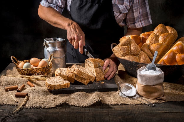 Baker, couper le pain sur une table rustique