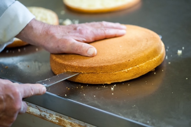 Baker Cutting Gâteau Cuit Au Four Frais Avec Un Couteau