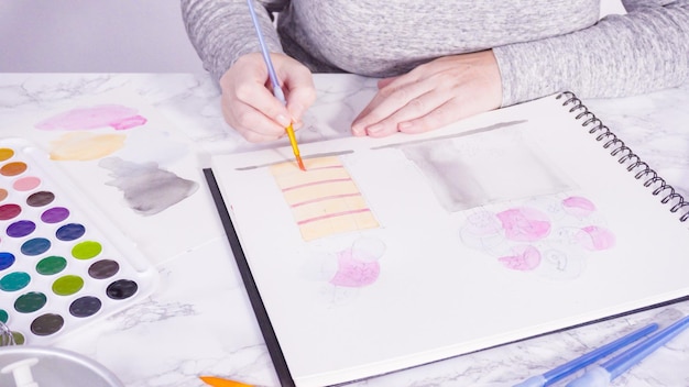 Baker dessine le dessin d'un gâteau d'anniversaire avec des aquarelles.