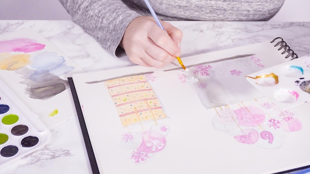 Baker dessine le dessin d'un gâteau d'anniversaire avec des aquarelles.