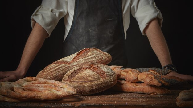 Baker avec du pain frais sur table marron en bois