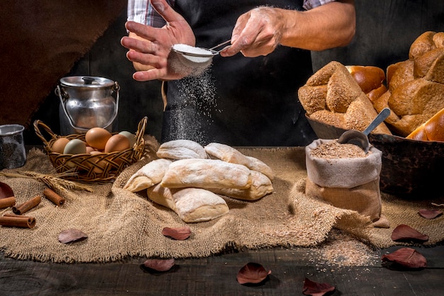 Baker jetant de la farine de blé sur du pain ciabatta.