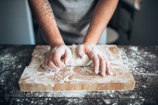 Baker mains pétrir la pâte avec de la farine