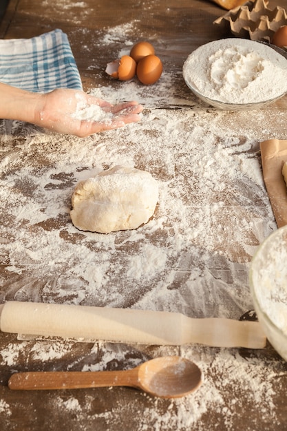 Baker met de la farine sur sa paume. Avec tous les ingrédients sur la table. Vue de côté.