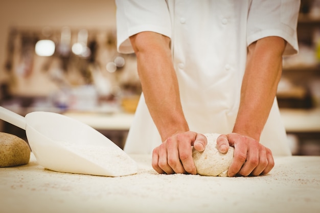 Baker pétrir la pâte à un comptoir