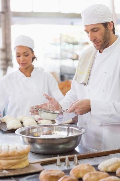 Baker tamisant la farine dans un bol