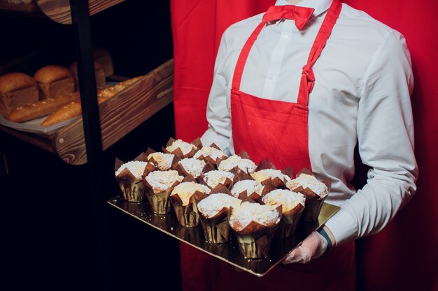 Baker tenant un plateau avec des cupcakes