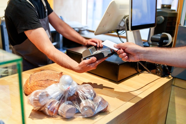 Baker039s Travailleur inconnu acceptant le paiement par carte pour des muffins et un pain au comptoir de la boulangerie