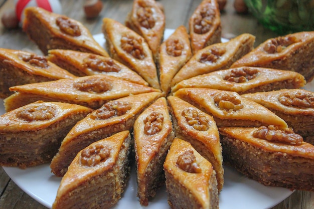 Photo baklava de biscuits de vacances traditionnelles de l'azerbaïdjan sur une plaque blanche sur le rustique avec des noix