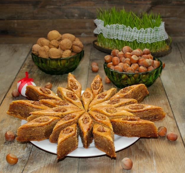 Photo baklava de biscuits de vacances traditionnelles de l'azerbaïdjan sur une plaque blanche sur le rustique avec des noix