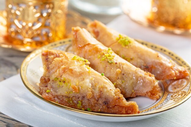 Baklava dessert arabe traditionnel avec noix de cajou, noix et cardamome avec une branche d'eucalyptus sur une table en bois