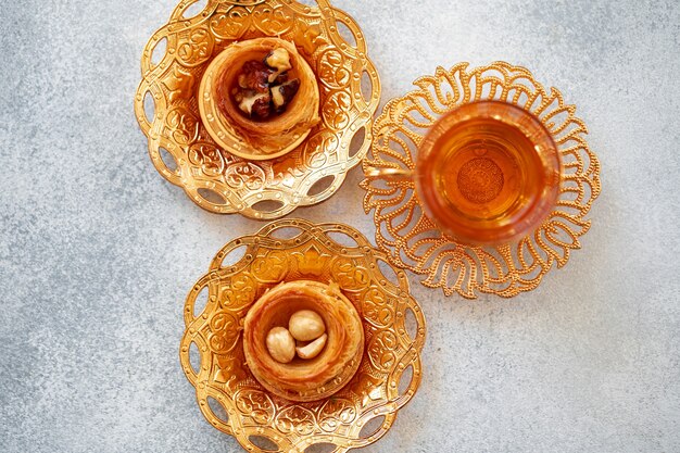 Baklava turc et thé turc dans des plats orientaux sur fond gris