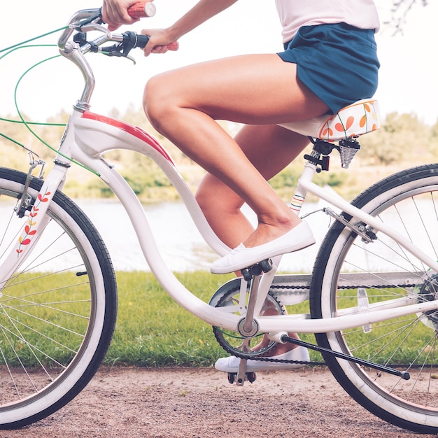 Balade en parc. Vue latérale en gros plan d'une jeune femme faisant du vélo dans un parc