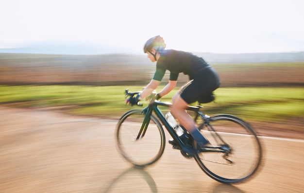 Balade à vélo en plein air et personne sur un vélo avec vitesse pour une course sportive sur une route de gravier Exercice de fitness et athlète rapide faisant de l'entraînement sportif dans la nature dans un parc pour un entraînement cardio et sain