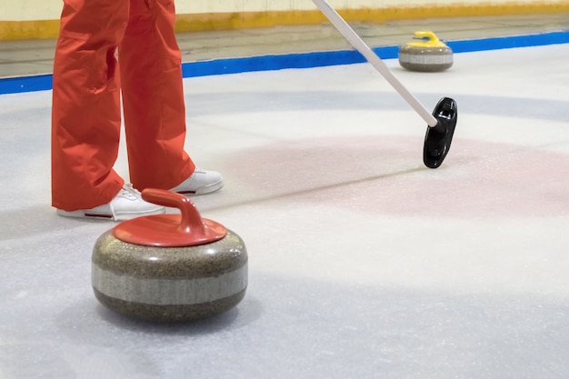 Balai et pierre pour le curling sur la glace d'une patinoire intérieure.