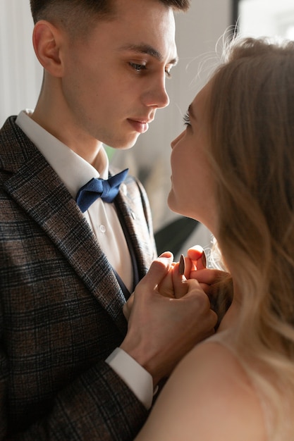 Le balai tient la mariée par les mains et la presse contre lui, la regardant dans les yeux