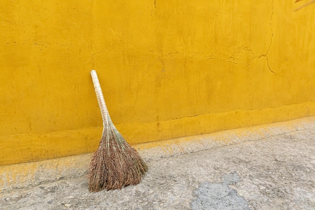 Un balai vintage et un seau en bois contre le mur de la grange