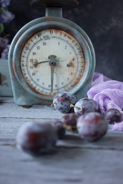 Balance vintage et prunes fraîches sur une table en bois