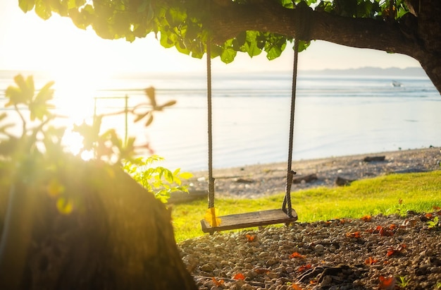 Balançoire au bord de la mer pendant le lever du soleil Ciel et reflets sur l'eau en été Rayons de soleil pendant le lever du soleil Nusa Penida Bali Indonésie Image de voyage