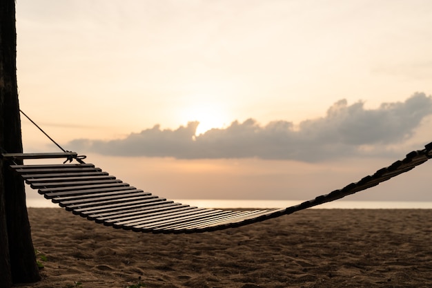 Une balançoire en bois ou un berceau sur la plage avec de beaux nuages et ciel.