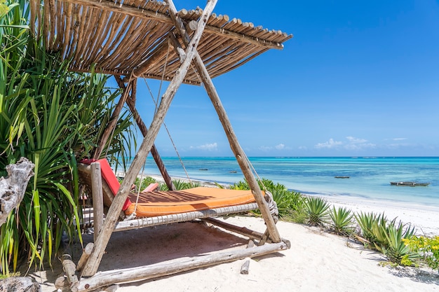 Balançoire en bois avec un matelas sous un auvent sur la plage tropicale près de la mer, île de Zanzibar, Tanzanie, Afrique de l'Est, concept de voyage et de vacances