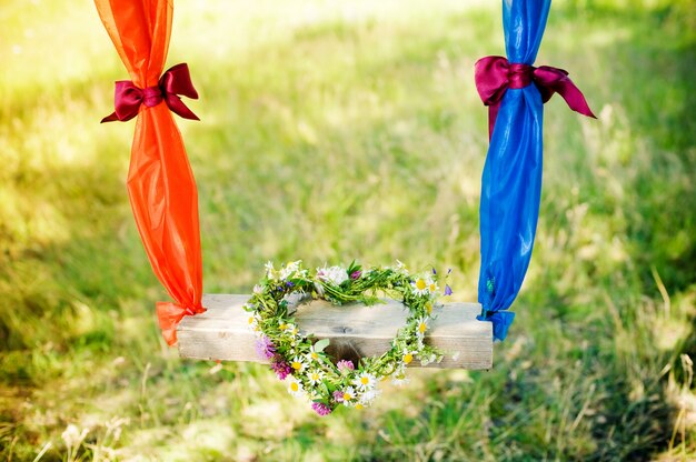 Sur une balançoire, une couronne de fleurs. cœur