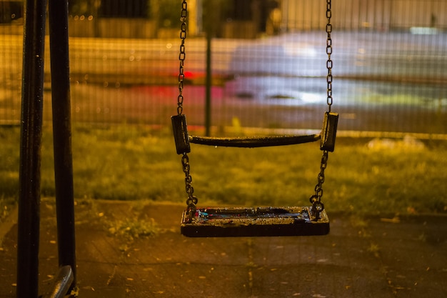 Une balançoire vide dans le parc la nuit pluvieuse