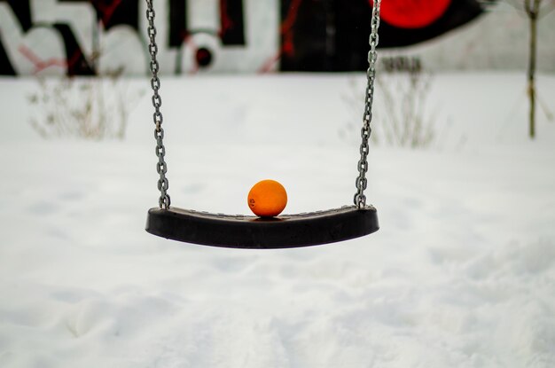 Une balançoire vide en hiver dans la rue.