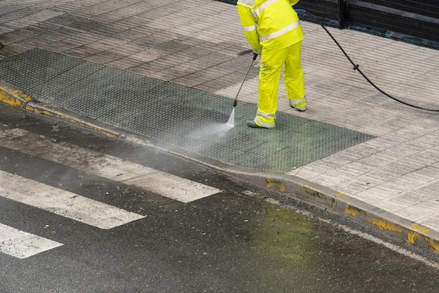 Balayeuse nettoyant un trottoir de rue avec un jet d'eau à haute pression