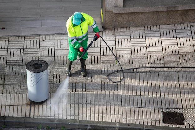 Balayeuse nettoyant un trottoir de rue avec une machine à jet d'eau haute pression. Entretien des rues