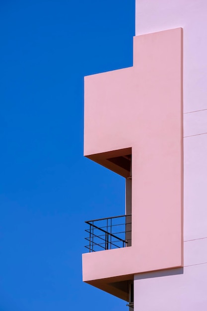 Balcon sur immeuble rose sur fond de ciel bleu clair dans le cadre vertical