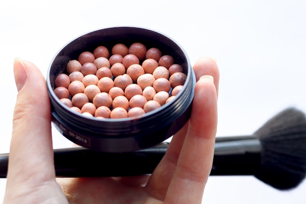 Ball blush à la main avec un pinceau sur fond blanc