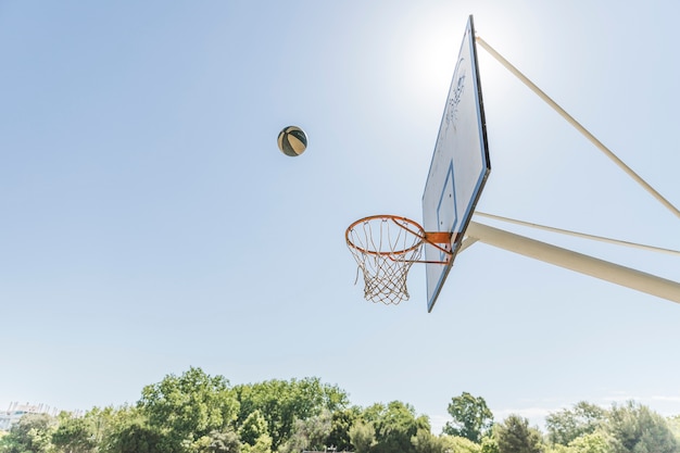 Photo balle dans l'air sur le cerceau de basket-ball contre le ciel bleu