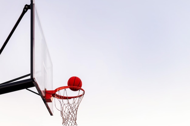 Balle entrant dans un panier de basket avec le ciel en arrière-plan concept de sport urbain à l'extérieur copiez l'espace pour le texte
