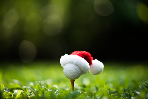 Balle de golf d'allure festive sur un tee-shirt avec le chapeau du père Noël au sommet pour la saison des vacances sur le parcours de golf