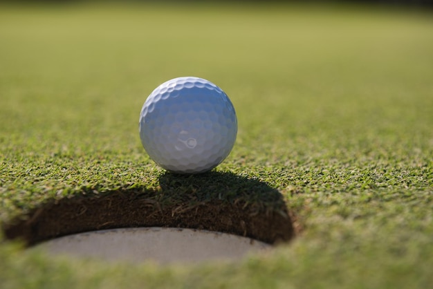 balle de golf sur le bord du trou du parcours représentant la réussite et le succès du concept d'entreprise