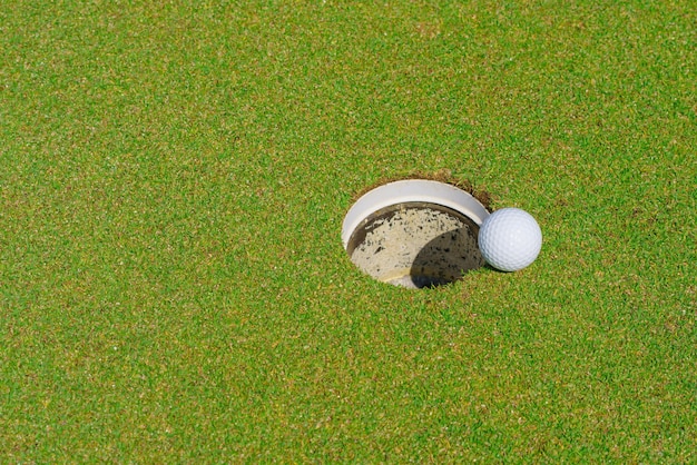 Photo la balle de golf sur la lèvre d'une tasse sur un terrain de golf