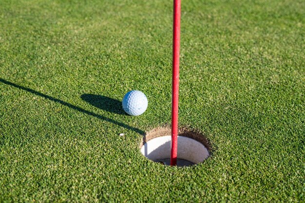 Une balle de golf située près d'un trou sur un terrain de golf