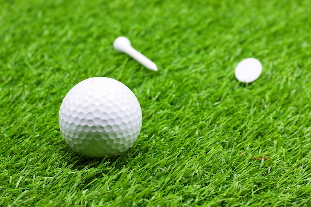 La balle de golf et le tee sont sur l&#39;herbe verte