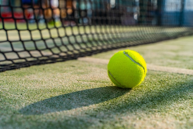 Balle de paddle-tennis sur le terrain avec le filet en arrière-plan et une belle lumière du soleil