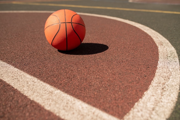 Balle pour jouer au basket allongé sur un terrain de sport ou un stade entre deux lignes blanches aux beaux jours