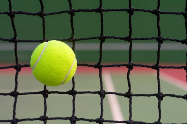 Balle de tennis frapper au filet sur fond de court de tennis flou